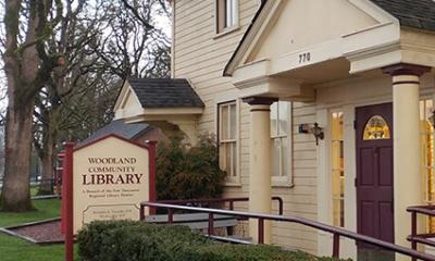 Outside front view of the Woodland Library sign and front entrance to the building